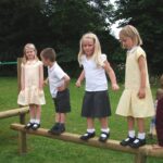 Children standing on balance beam for adventure trail playground equipment