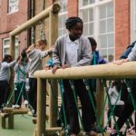 School children playing on wobbly bridge school playground equipment