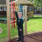 Child trying to hit the top of the post mounted chimes