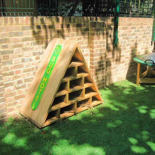 The bug hotel infront of a wall in a school playground