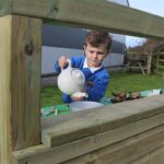 Boy Playing In Mud Kitchen