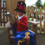 A girl sitting on storyteller's chair reading a book