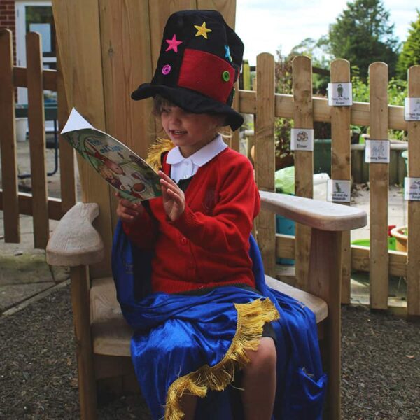 A girl sitting on storyteller's chair reading a book