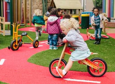 Child on a bike riding around a small red road