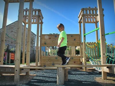 Child walking on a wooden beam of a playpark